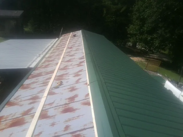 Old rusted panels beside newly installed green metal roofing — Wind Damage Roof Repair by Roofing Brothers in South Lancaster