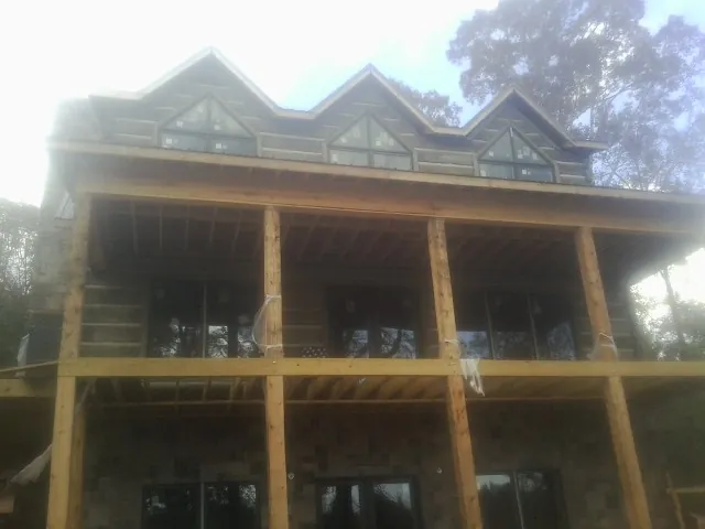 Dormers and porch framing on a large log home under construction — Roof Coating work by our crew in South Lancaster