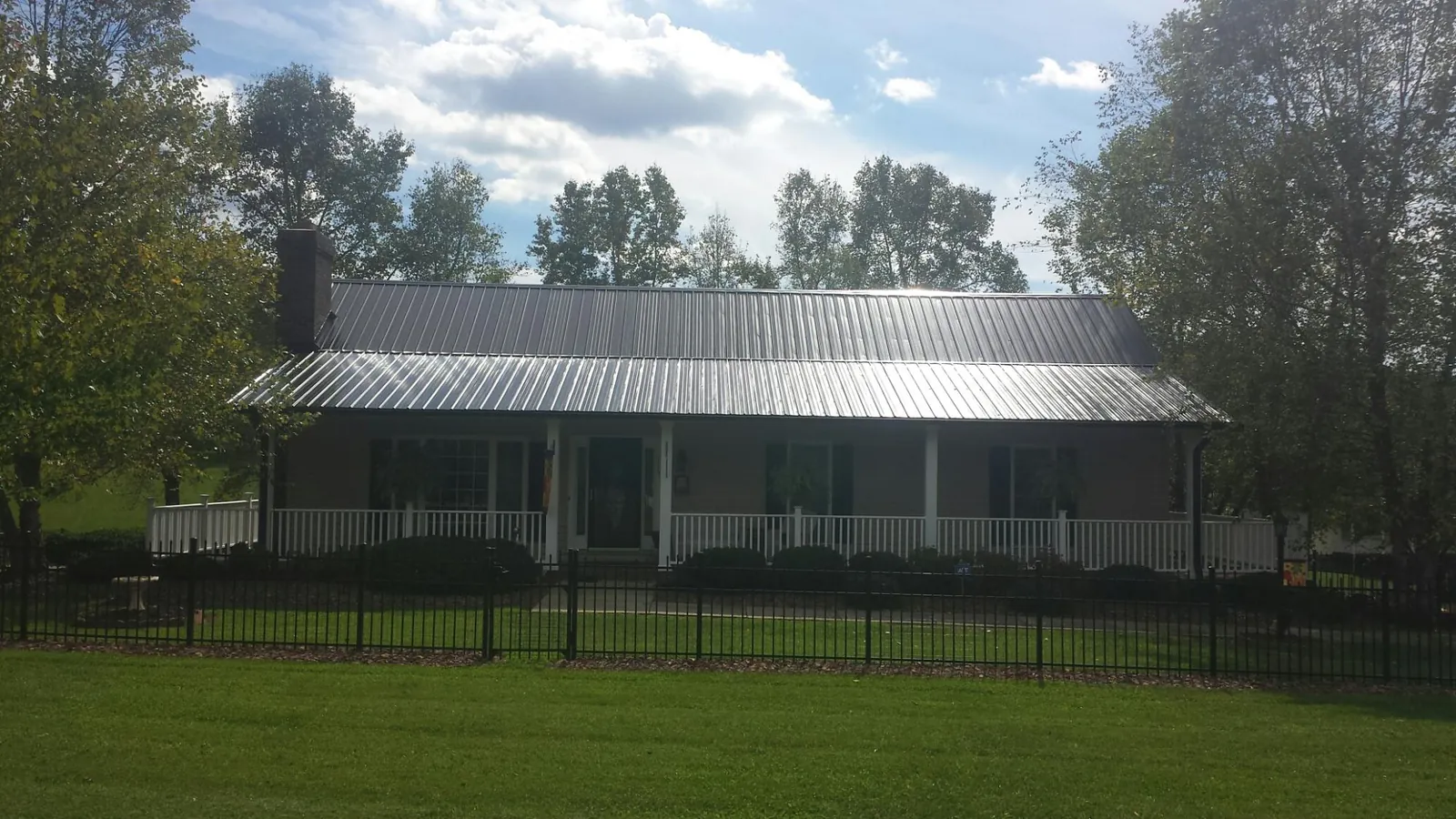 Gray metal roof on a brick ranch with a full width front porch — Gutter Guard Installation work by our crew in South Lancaster