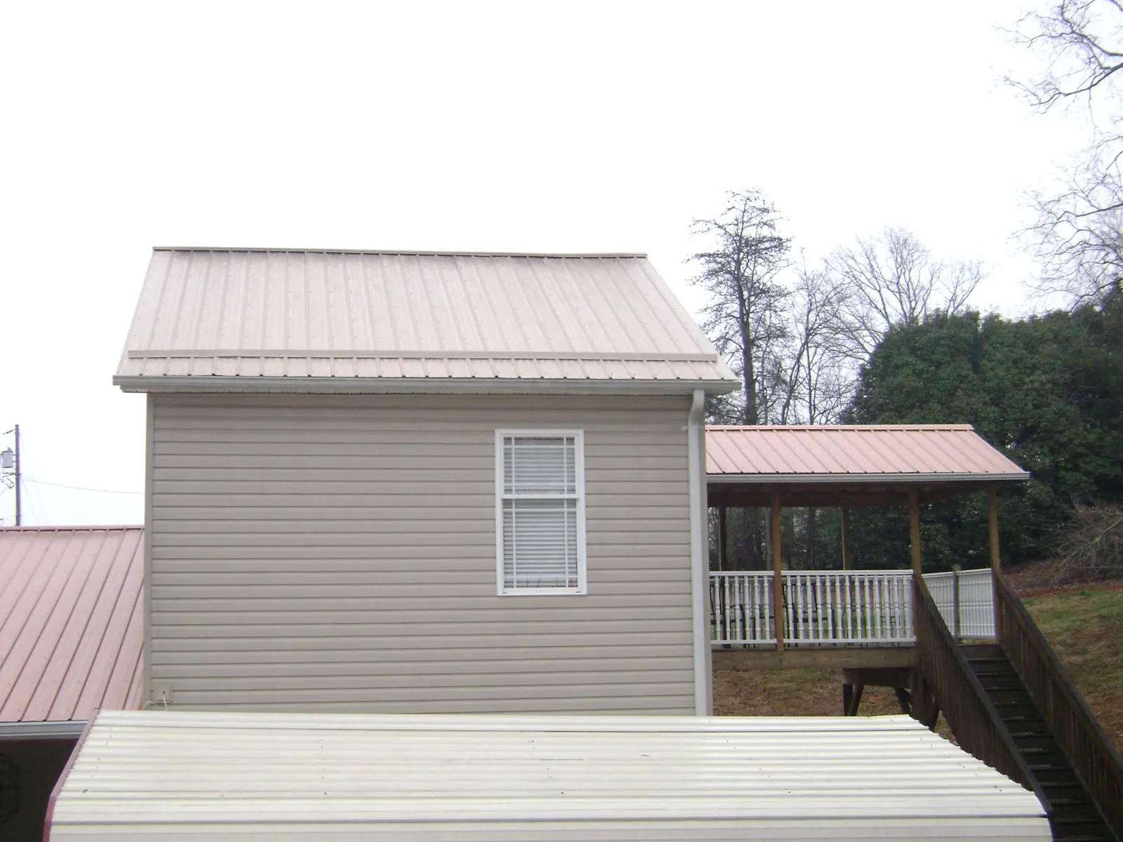 Tan metal roofs on a two story addition and attached porch, from a Roof Replacement job in South Lancaster