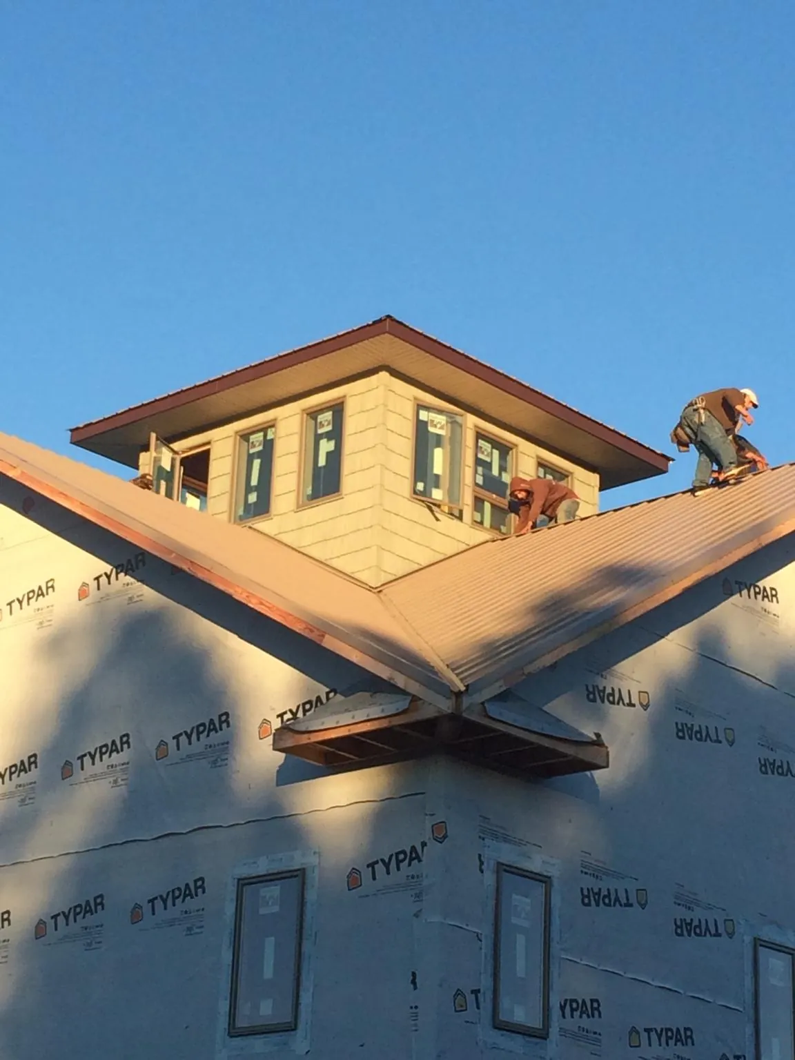 Roofers working around a rooftop cupola on a new metal roof at sunset — Roof Waterproofing in South Lancaster by Roofing Brothers